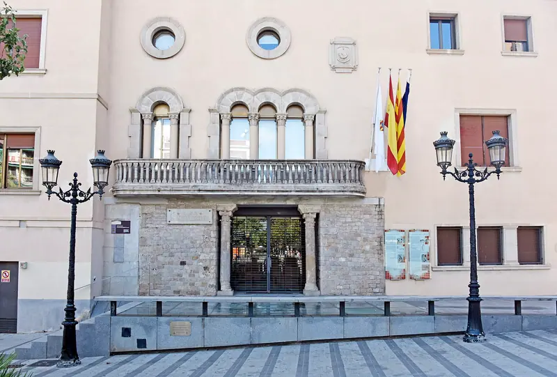 Fachada del Ayuntamiento de Cornellà de Llobregat con balcón de arcos, farolas de forja y banderas