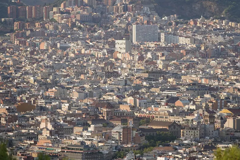 Vista desde lo alto de los edificios del Eixample, con la montaña al fondo y torres de viviendas entre manzanas densas