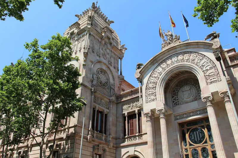 Fachada modernista del Palau de Justícia de Barcelona, con su arco de entrada y torres, entre árboles