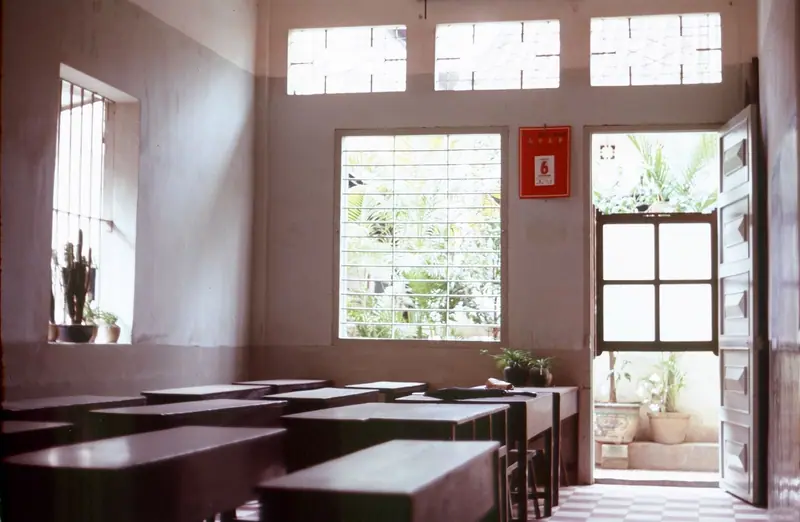Aula vacía de una escuela de idiomas, con pupitres en filas y luz natural que entra por las ventanas