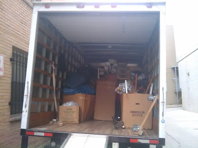 Caja de carga de un camión de mudanzas abierta por detrás, con cajas de cartón y muebles protegidos